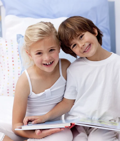 Happy brother and sister reading a book in bedroom — Stock Photo, Image
