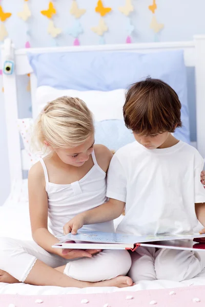 Brother and sister reading a book in bedroom — Stock Photo, Image