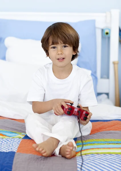Мальчик, сидящий в постели и играющий в видеоигры — стоковое фото