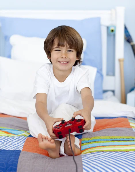 男孩玩游戏坐在他的床 — 图库照片