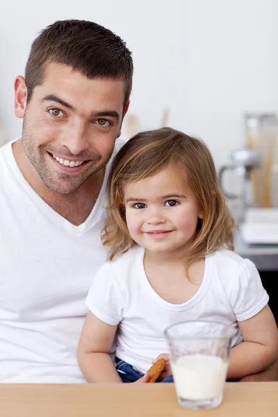 Усміхнений тато і маленька дівчинка їдять печиво з молоком — стокове фото