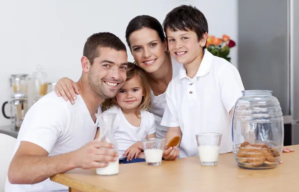 Familia feliz comiendo galletas y bebiendo leche — Foto de Stock