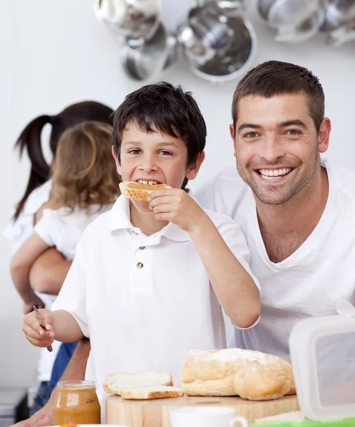 Father and son eating a toast in breakfast time — Stock Photo, Image