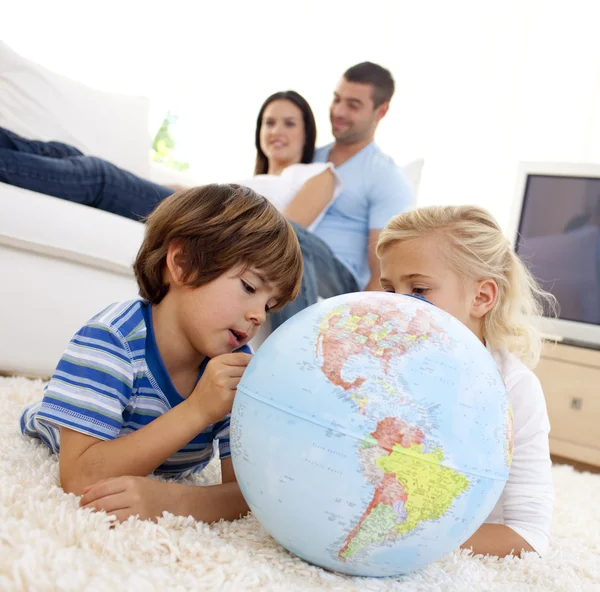 Crianças brincando com um globo terrestre na sala de estar — Fotografia de Stock