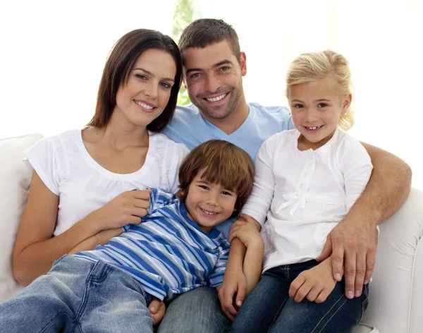 Sonriente joven familia sentada en el sofá —  Fotos de Stock