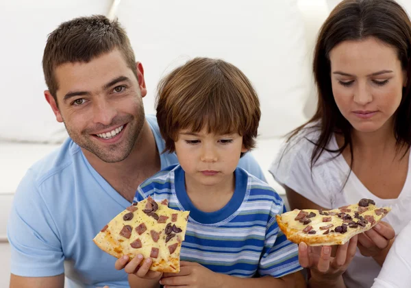 Prents e menino comendo pizza na sala de estar — Fotografia de Stock