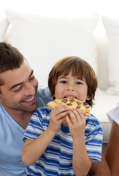 Chłopiec jedzenie pizzy w salonie z ojcem — Zdjęcie stockowe