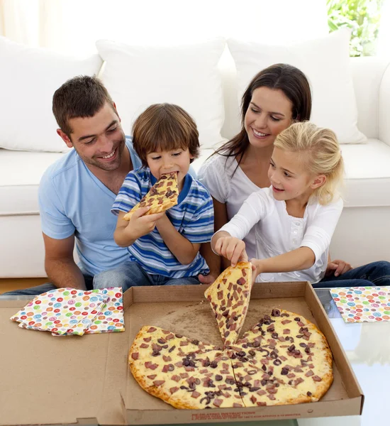Молодая семья ест пиццу в гостиной — стоковое фото