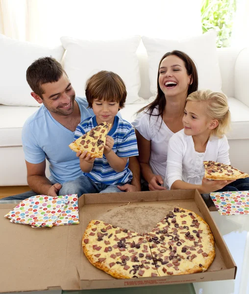 Rodiče a děti jíst pizzu v obýváku — Stock fotografie
