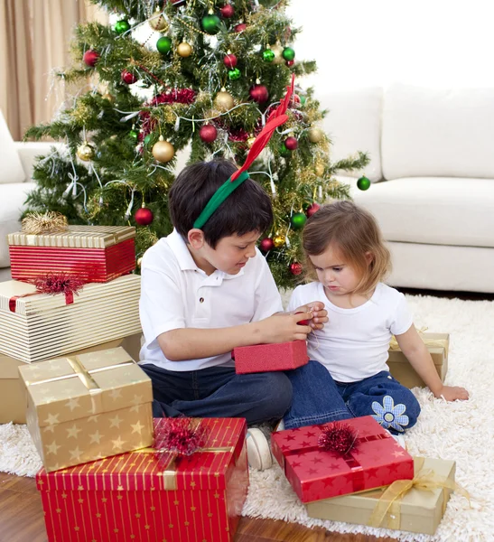 Joyeux frère et sœur regardant cadeaux de Noël — Photo