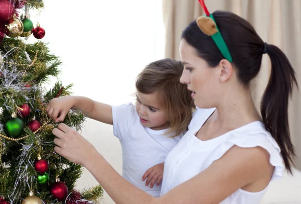 Mor och dotter dekorerar en julgran — Stockfoto