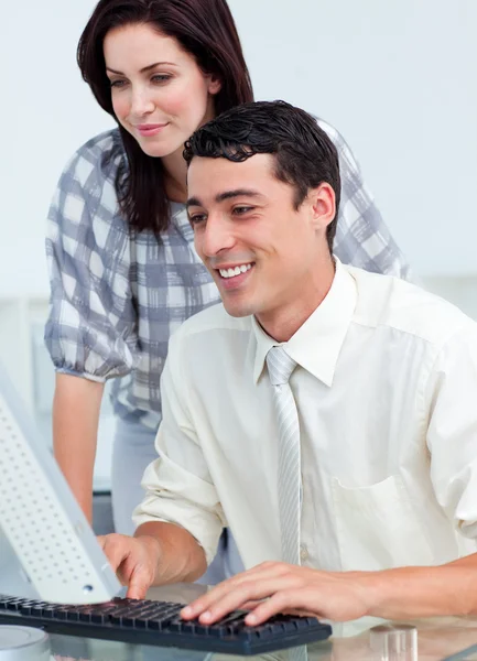 Attractive businesswoman helping her colleague at a computer Stock Picture