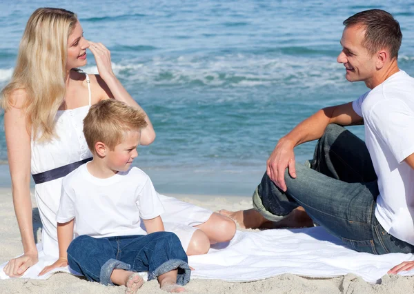 Smiling parents with their son sitting on the sand Royalty Free Stock Images