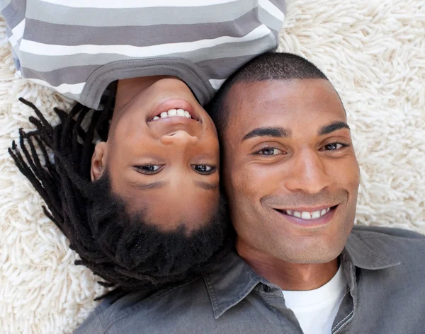 Smiling Afro-American father and son lying on the floor — Stock Photo, Image