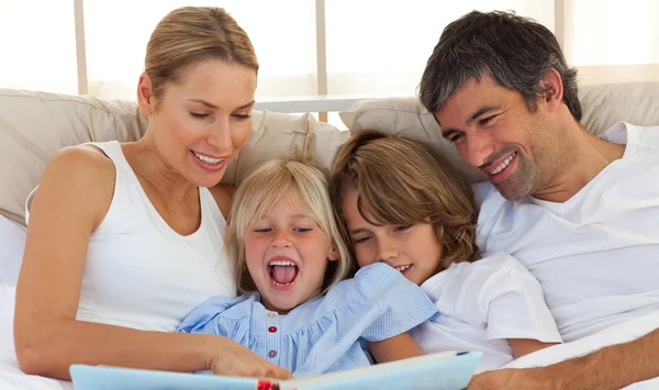 Jolly family reading a book on bed — Stock Photo, Image