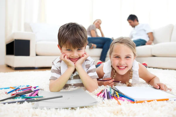 Smiling siblings drawing lying on the floor — Stock Photo, Image