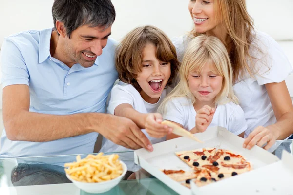 Excited children eating a pizza with their parents Royalty Free Stock Images