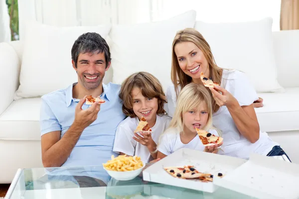 Smiling family eating a pizza sitting on the floor Stock Image