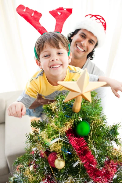 Vader en zoon versieren van een kerstboom Stockafbeelding