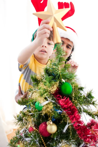 Father and son putting a star on the top of a Christmas tree Stock Image