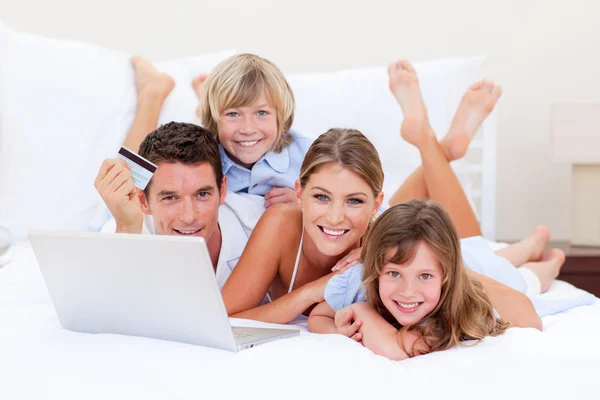 Enthusiastic family buying online lying down on bed — Stock Photo, Image