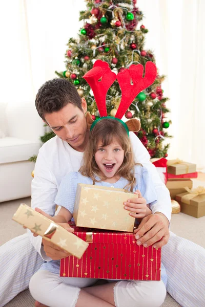 Удивлённая маленькая девочка открывает подарки со своим отцом Лицензионные Стоковые Фото
