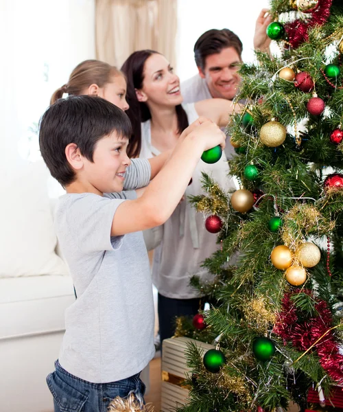 Gelukkig familie versieren een kerstboom met boubles Stockafbeelding