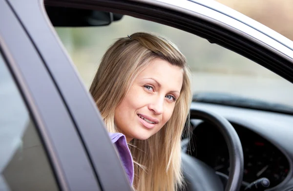 Attraktive junge Fahrerin sitzt in ihrem Auto Stockbild