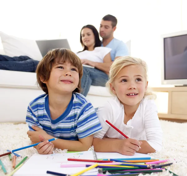 Children painting in living-room and parents on sofa — Stock Photo, Image