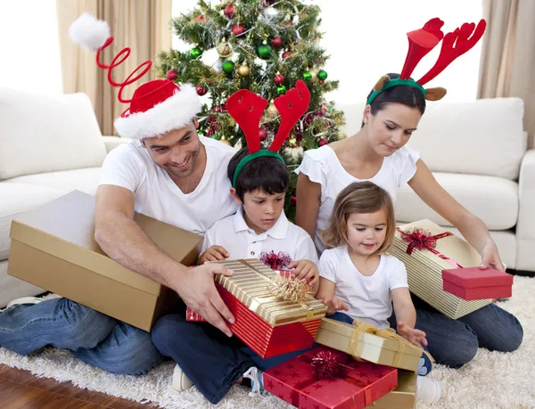 Lycklig familj öppnar jul presenterar hemma Stockbild