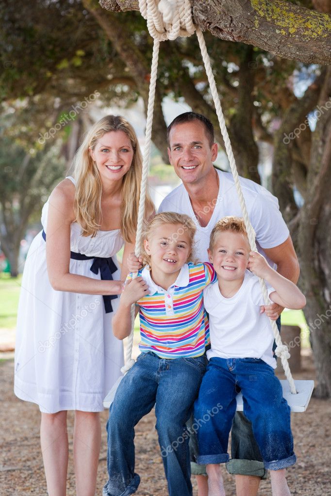 Attentive Parents Pushing Their Children On A Swing Stock Photo By C Wavebreakmedia