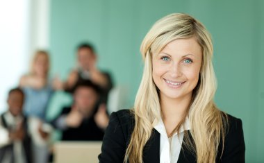 Businesswoman in front of her team in an office clipart