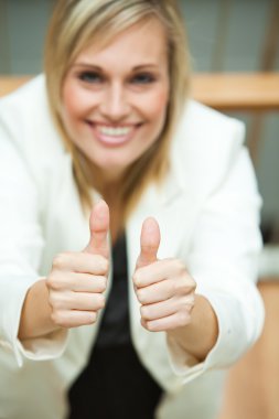 Businesswoman smiling at the camera with her thumbs up clipart