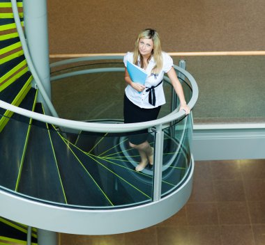 Businesswoman walking up stairs in office clipart