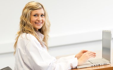 Beautiful female surgeon working on a laptop clipart