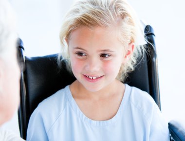 Blond little girl sitting on a wheelchair clipart