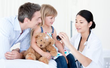 Concentrated asian female doctor giving syrup to a little girl clipart