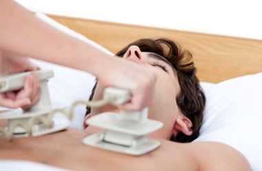 Male doctor using the defibrillator to reanimate an inconscious clipart