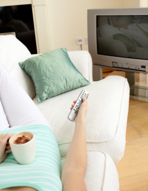 Woman drinking a coffee while watching TV clipart