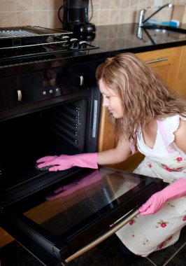 Young woman cleaning the oven clipart