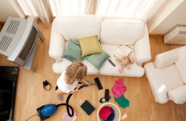 Blond woman vacuuming the living-room clipart