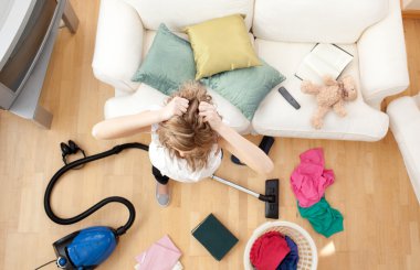 Depressed blond woman vacuuming the living-room clipart