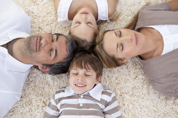 Family sleeping on floor with heads together — Stock Photo, Image
