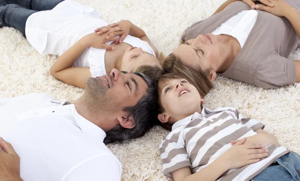 Familia acostada en el suelo en casa con cabezas juntas —  Fotos de Stock