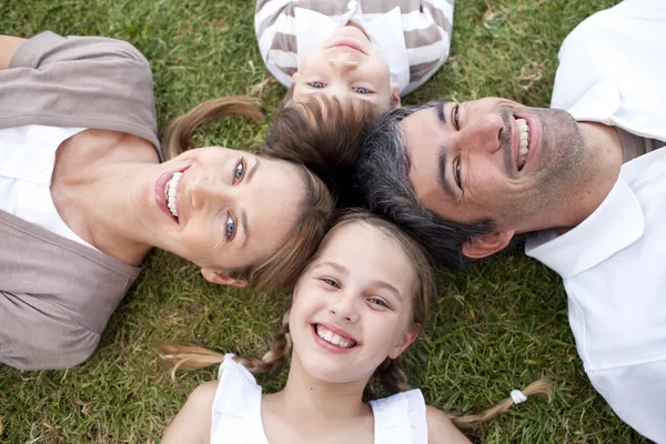 Lachende familie liggen buiten — Stockfoto