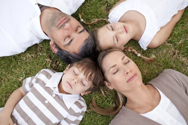 Família dormindo em um parque com cabeças juntas — Fotografia de Stock