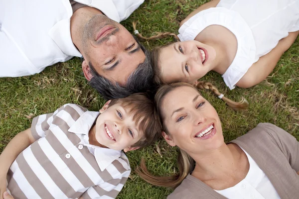 Lachende familie liggen in een park — Stockfoto