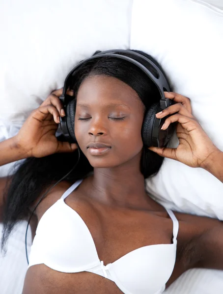 Strahlende Frau hört Musik liegend auf ihrem Bett — Stockfoto