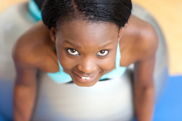 微笑有吸引力的女人做俯卧撑的健身房球 — 图库照片