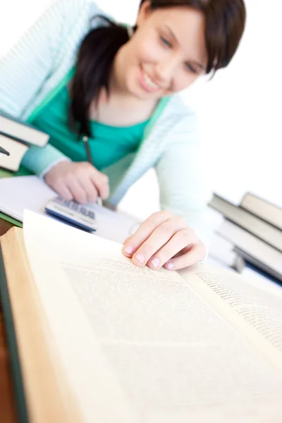 Веселая студентка делает домашнее задание на столе — стоковое фото